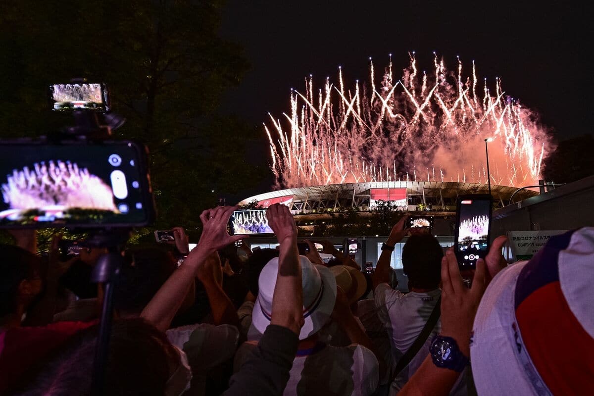 Des spectateurs prennent des photos devant le Stade olympique alors que débute la cérémonie d'ouverture.