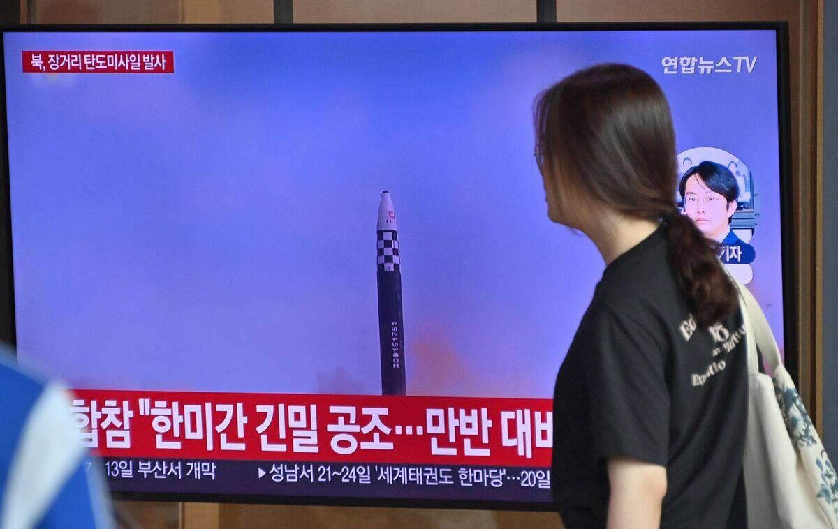Une femme marche devant une télévision à Séoul montrant les images du tir de missile nord-coréen le 12 juillet 2023