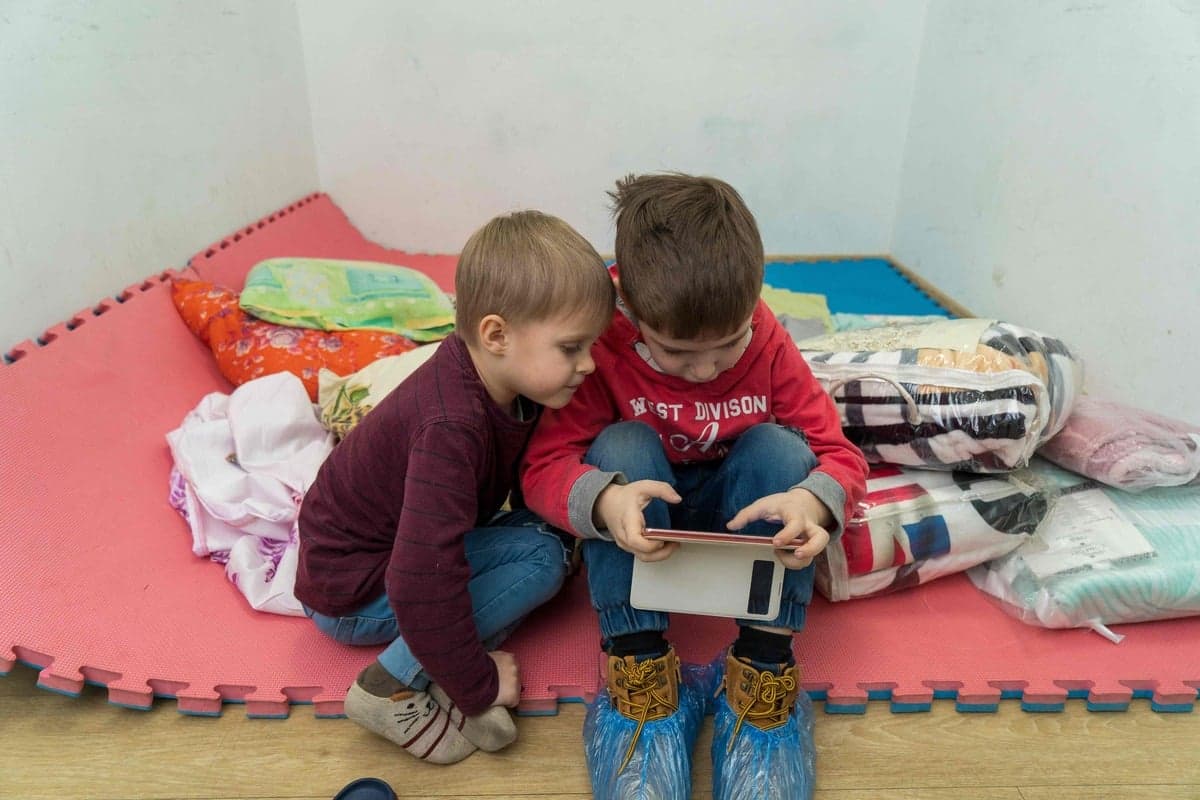 Des enfants jouent avec un téléphone intelligent dans un refuge situé dans la Ville de Dinpro.