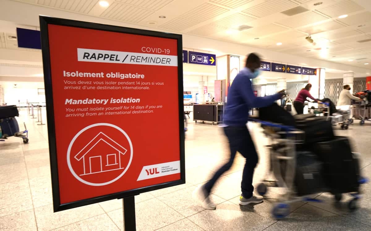 Dans cette photo prise en décembre 2020 à l'Aéroport international Montréal-Trudeau, un panneau rappelle les mesures d'isolement à la maison obligatoires aux voyageurs.