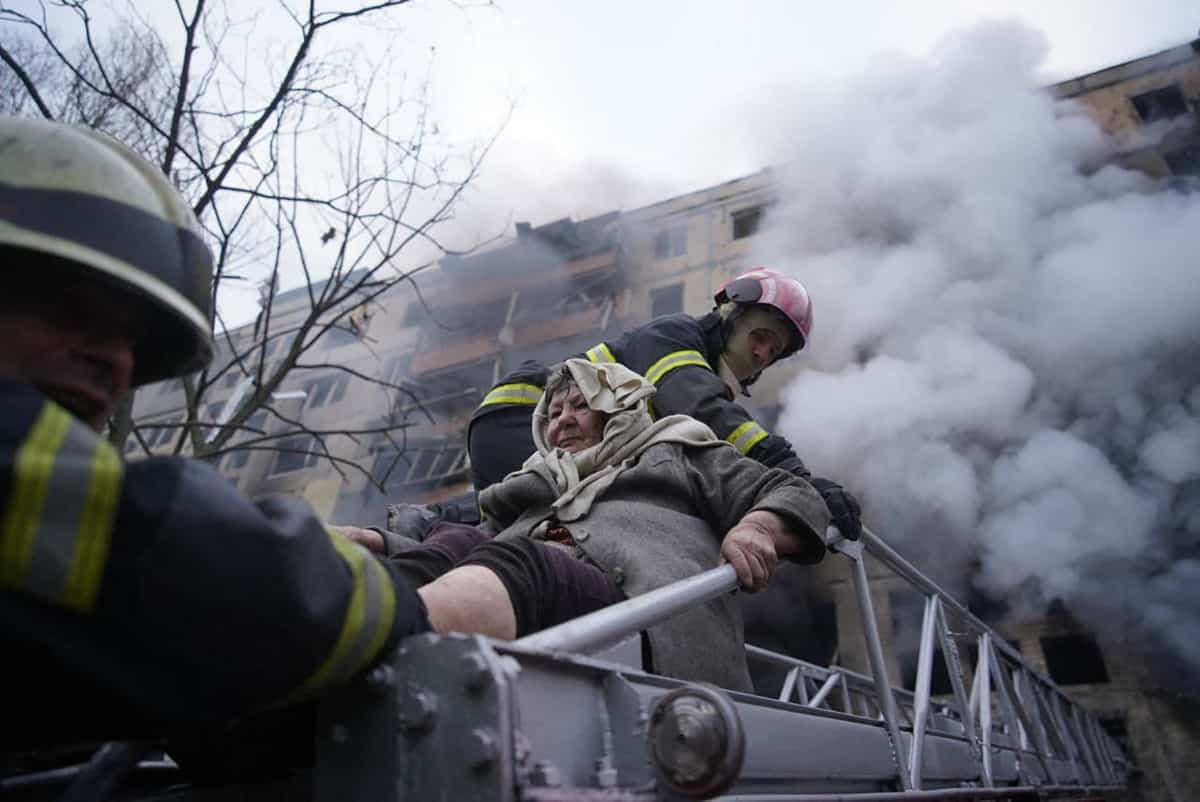 Des pompiers évacuent une femme après le bombardement de son bloc appartement à Kyïv.