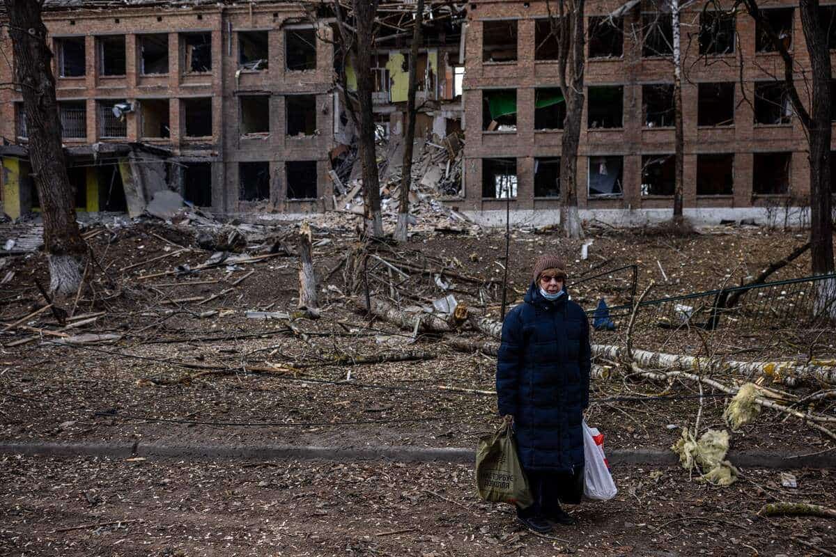 Une femme devant un immeuble endommagé par un missile, en Ukraine.