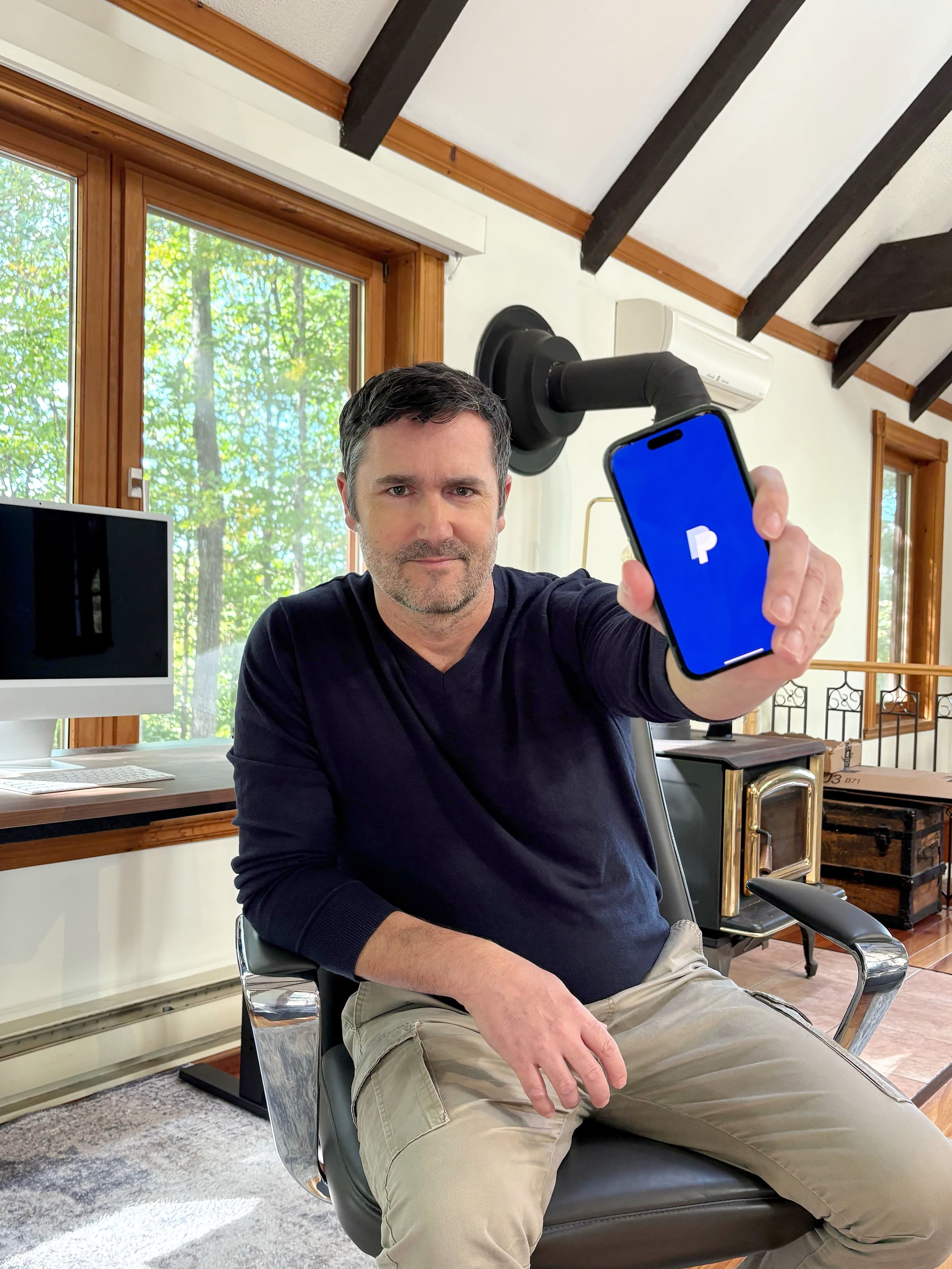 Dany Papineau, fondateur de WeChalet, brandit son téléphone pour montrer l'écran PayPal qu'il blâme pour les problèmes de son entreprise.