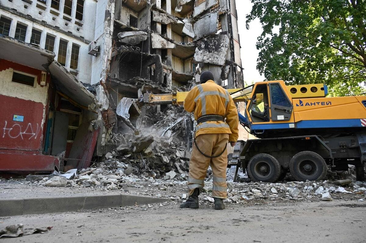 Un secouriste nettoie les débris d'un bâtiment résidentiel partiellement détruit par un bombardement en banlieue de Kharkiv.