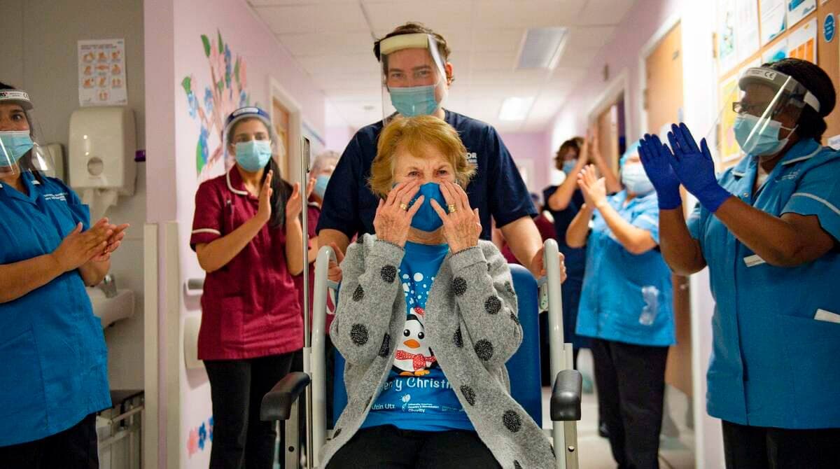 Margaret Keenan, âgée de 90 ans, est applaudie par du personnel hospitalier après être devenue la première personne a avoir reçu le vaccin de Pfizer/BioNtech en Angleterre, le 8 décembre 2020.