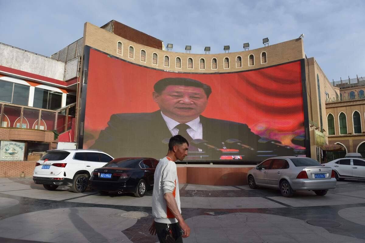 Photo prise le 4 juin 2019 montre un homme passant devant un écran montrant des images du président chinois Xi Jinping à Kashgar, dans la région du Xinjiang, dans le nord-ouest de la Chine: AFP_1IK39F