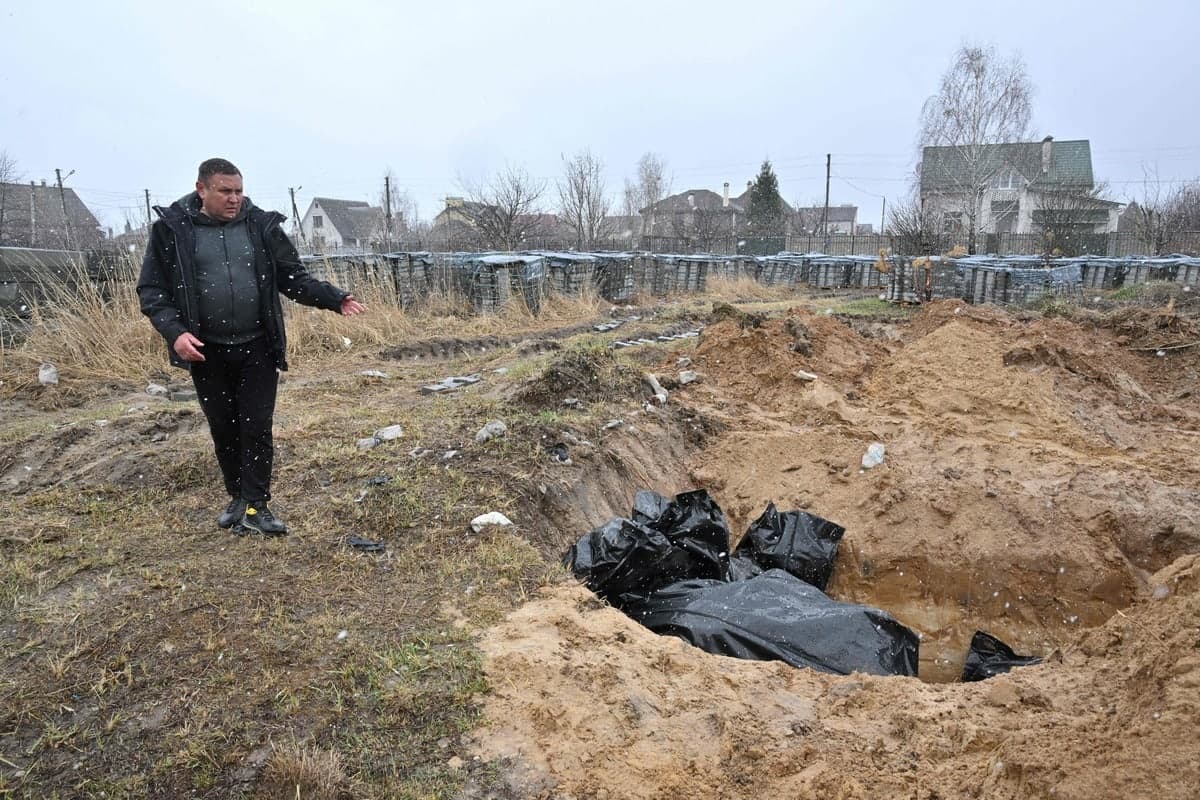 Un homme montre une fosse commune à Boutcha.