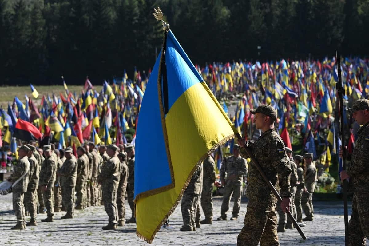 Un soldat ukrainien porte le drapeau national lors d'une cérémonie funéraire pour les militaires ukrainiens Volodymyr Pugolovko, Yuriy Shumalo et Yuriy Cheliapin au cimetière militaire de Lychakiv à Lviv, le 20 septembre 2024, au milieu de l'invasion russe en Ukraine.