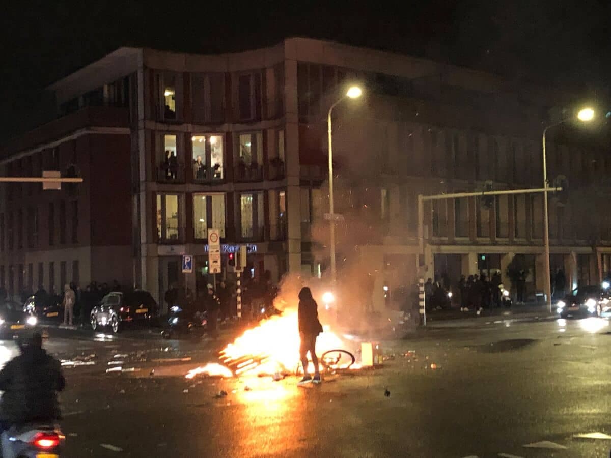 Un homme marche devant un feu dans une rue de La Haye, lors d'une manifestation contre les mesures du gouvernement néerlandais contre le coronavirus, le 20 novembre 2021. (Photo par Danny KEMP / AFP)