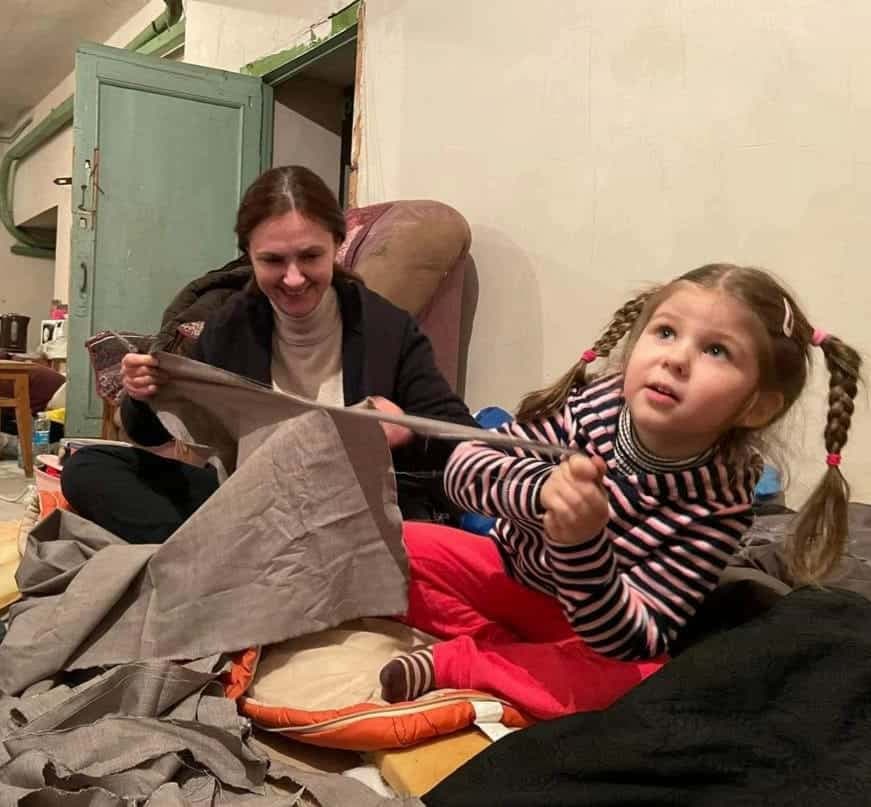 Bogdana et une enfant de son bunker fabriquent un filet de camouflage pour les soldats ukrainiens.