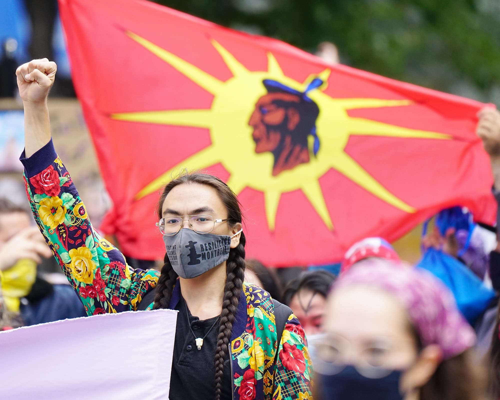 Une manifestante à Montréal devant le drapeau des Warriors mohawks.