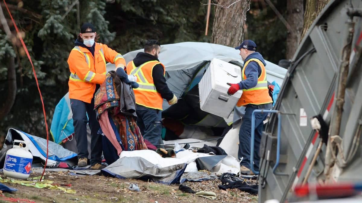 Des cols bleus s’affairent à nettoyer le campement Notre-Dame après son démantèlement par la police.