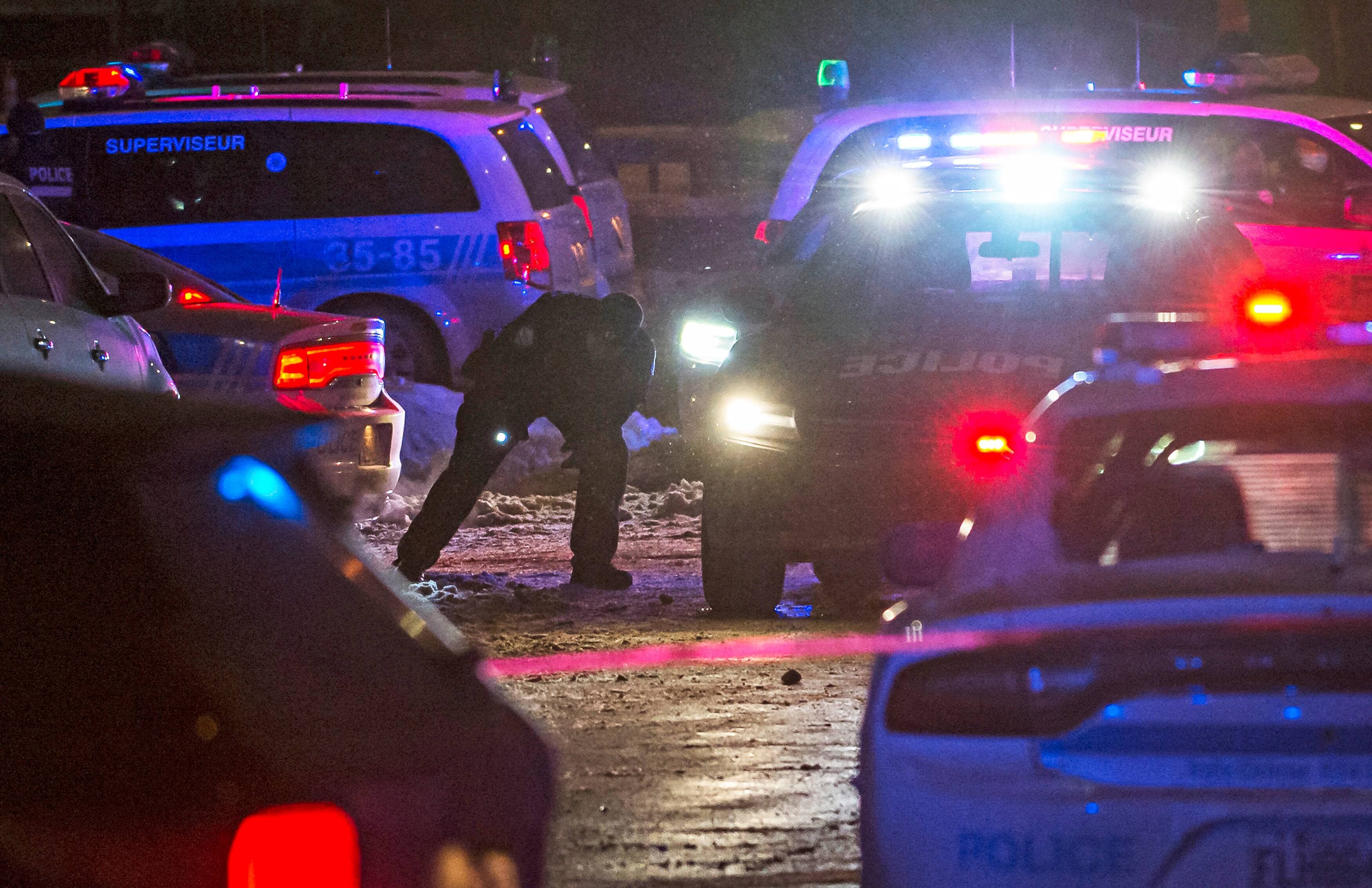 Un policier fouille sous une voiture à l’aide d’une lampe de poche sur le boulevard Crémazie Ouest à Montréal, où un policier a été blessé lors d’une bagarre avec un chauffeur Uber, jeudi.