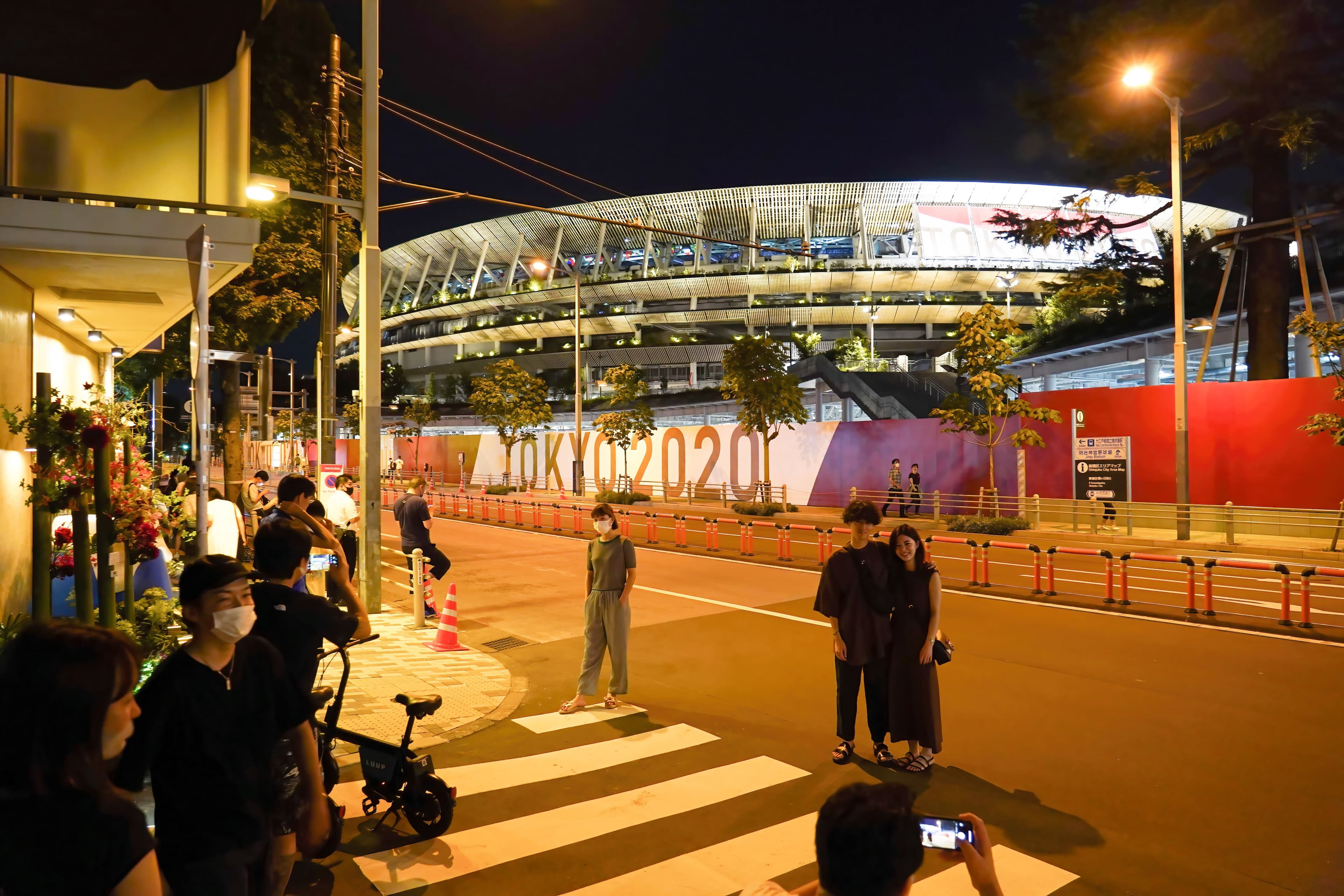 Avec ou sans masque, des visiteurs se laissaient photographier devant le Stade olympique de Tokyo, jeudi.