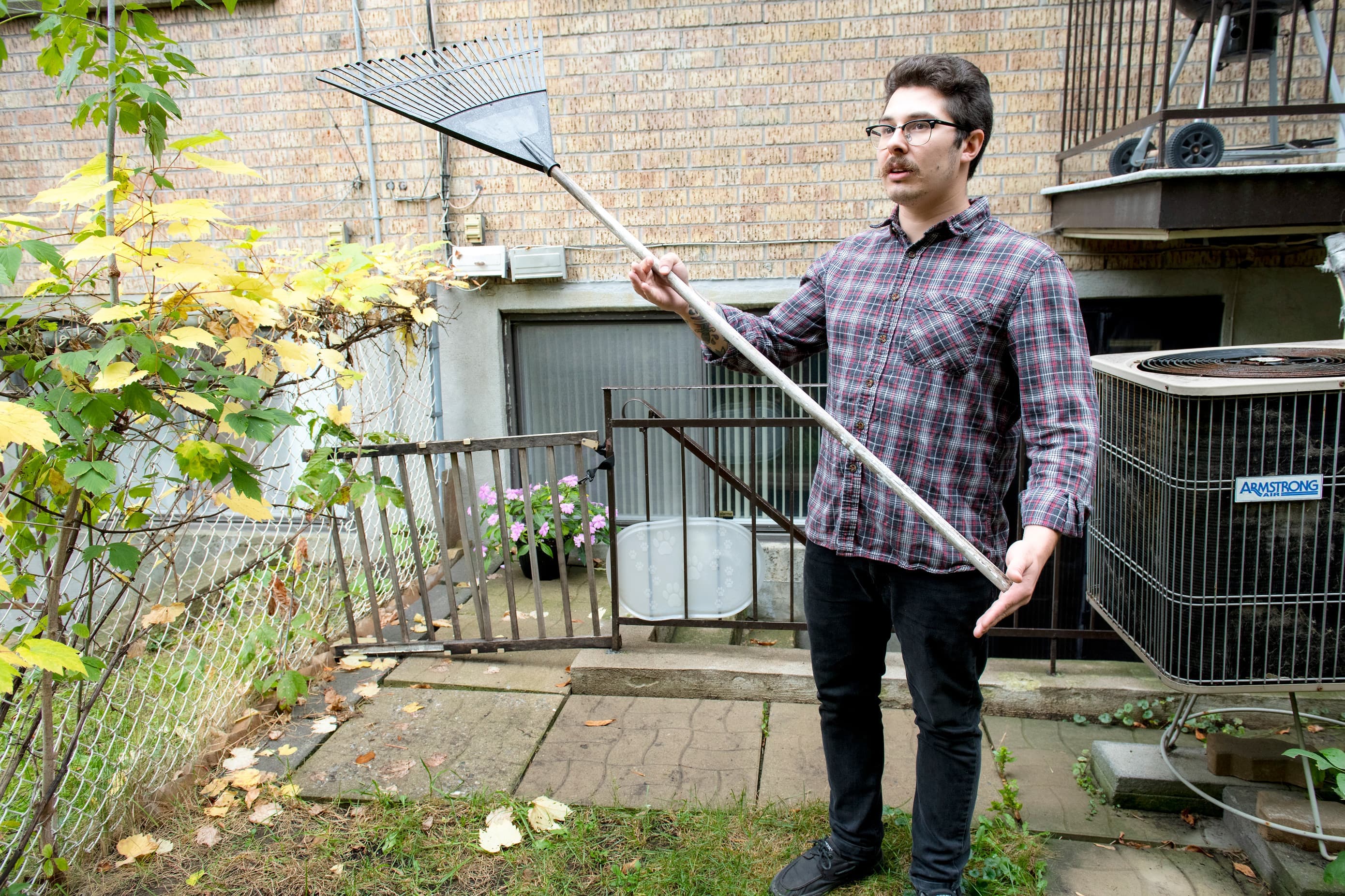 Justin Addison montre avec ses mains la longueur de la craque entre sa cour et son immeuble.