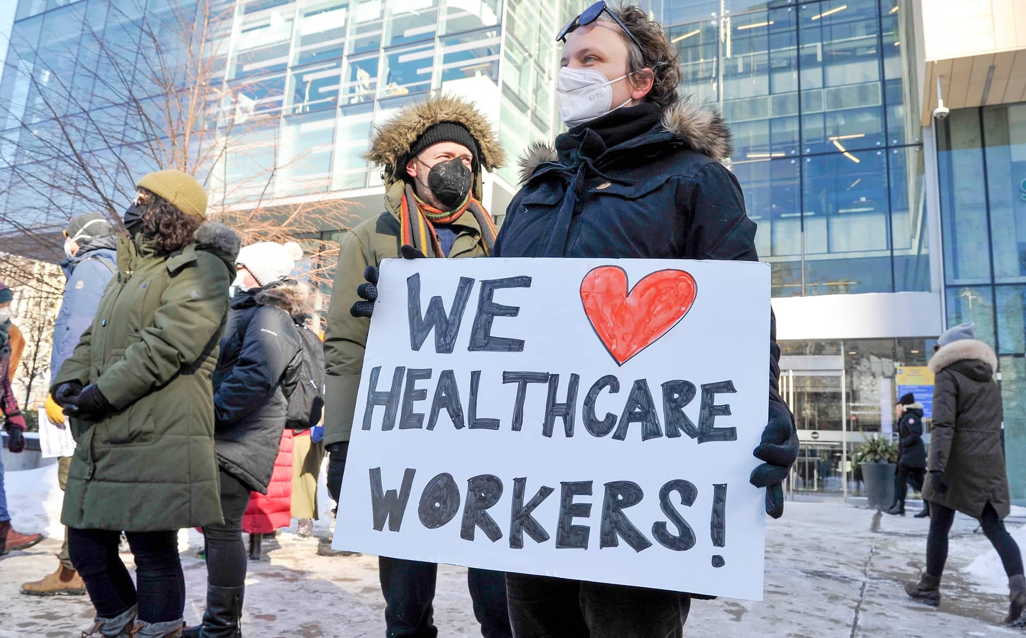 Un Torontois montre son soutien aux travailleurs de la santé, à côté du convoi dans sa ville.