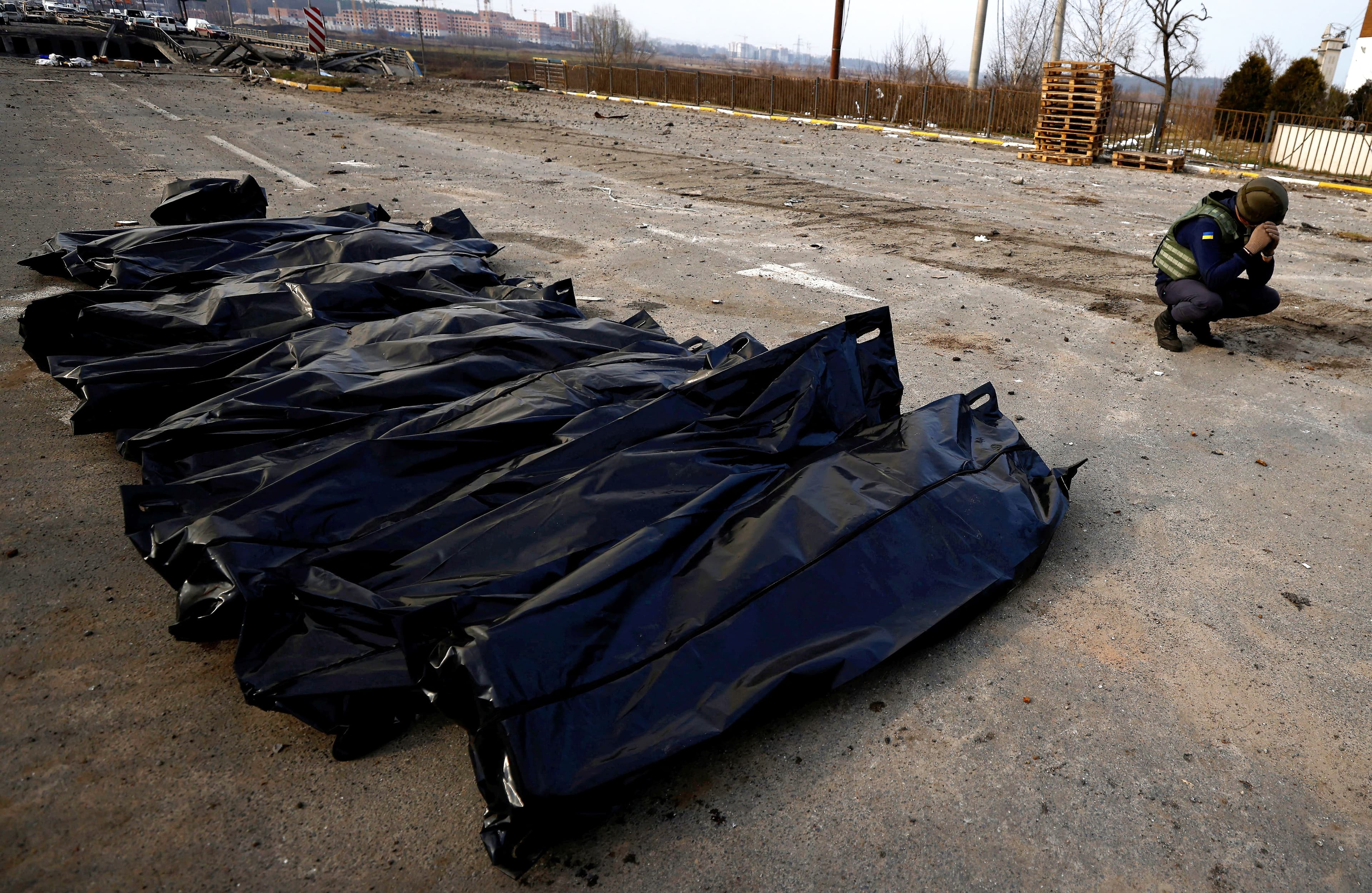 Un membre des services d’urgence prend une pause à côté de sacs contenant le corps de civils tués par des bombardements russes, à Irpin près de Kyïv, avant qu’ils soient transportés à la morgue.