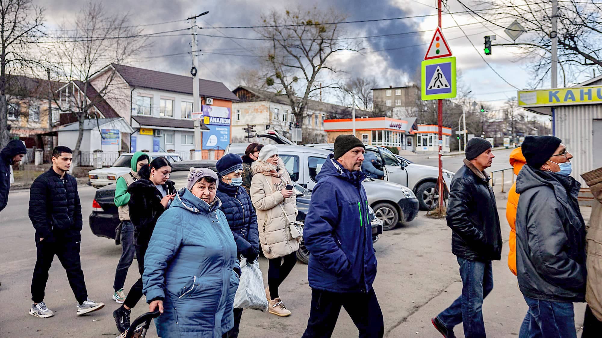 Des gens font la file devant une épicerie de Vassylkiv. Le nuage de fumée provient d’un dépôt de pétrole détruit par les Russes, la veille.