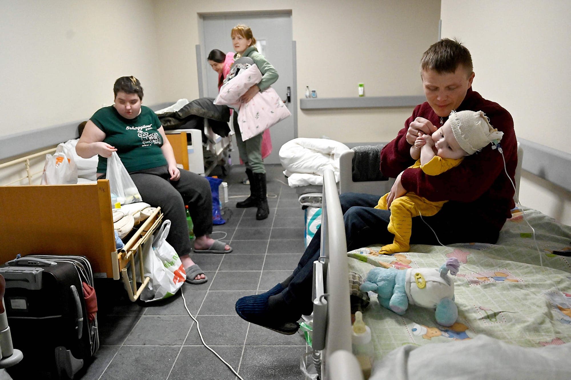 Des parents et leurs enfants, patients de l’hôpital central pour enfants de Kyïv, récupèrent leurs effets personnels avant leur évacuation vers la Pologne et l’Allemagne.