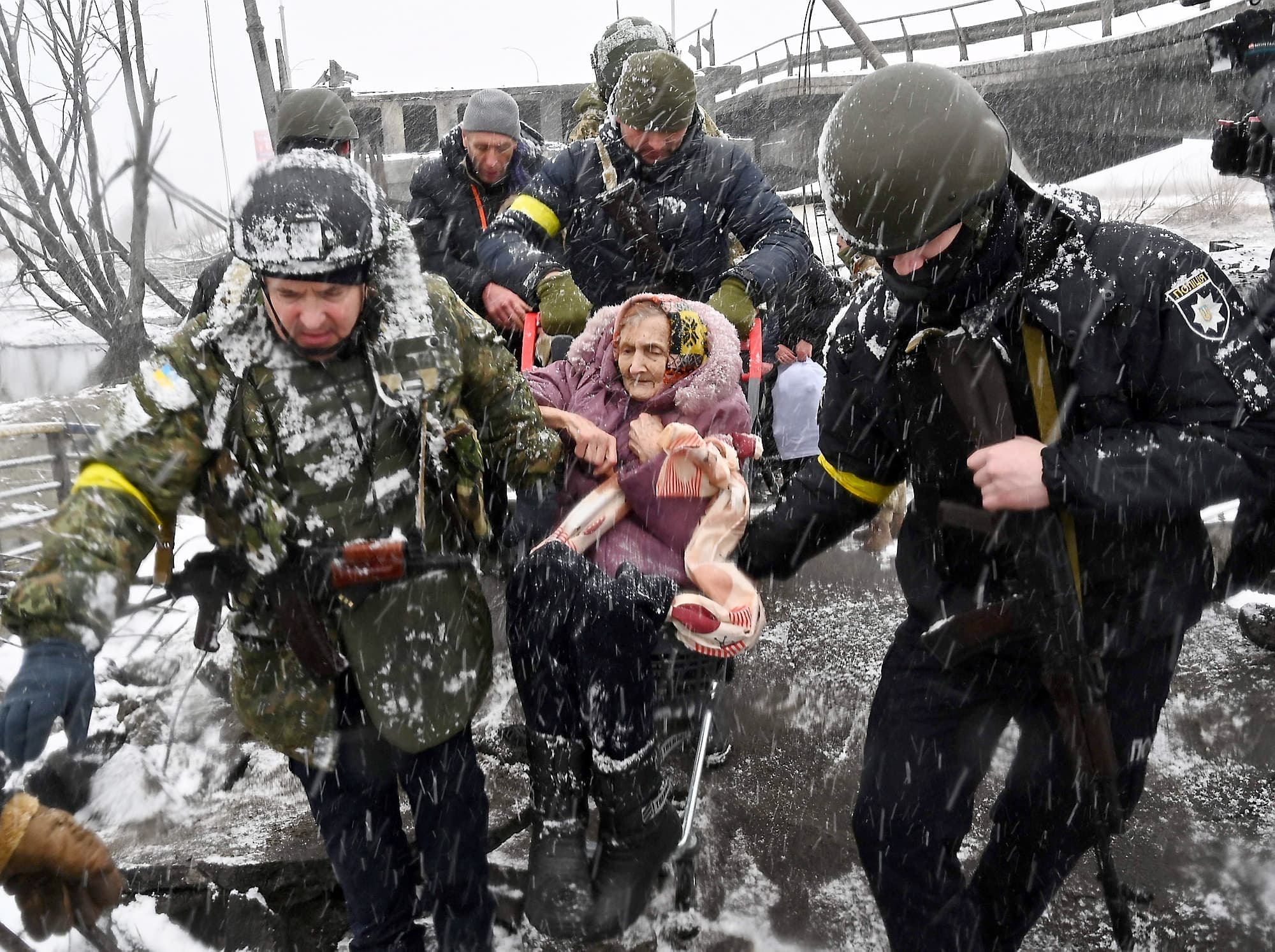 Sous les précipitations de neige, des soldats aidaient hier une dame à traverser dans un chariot un pont détruit dans la ville d’Irpin.