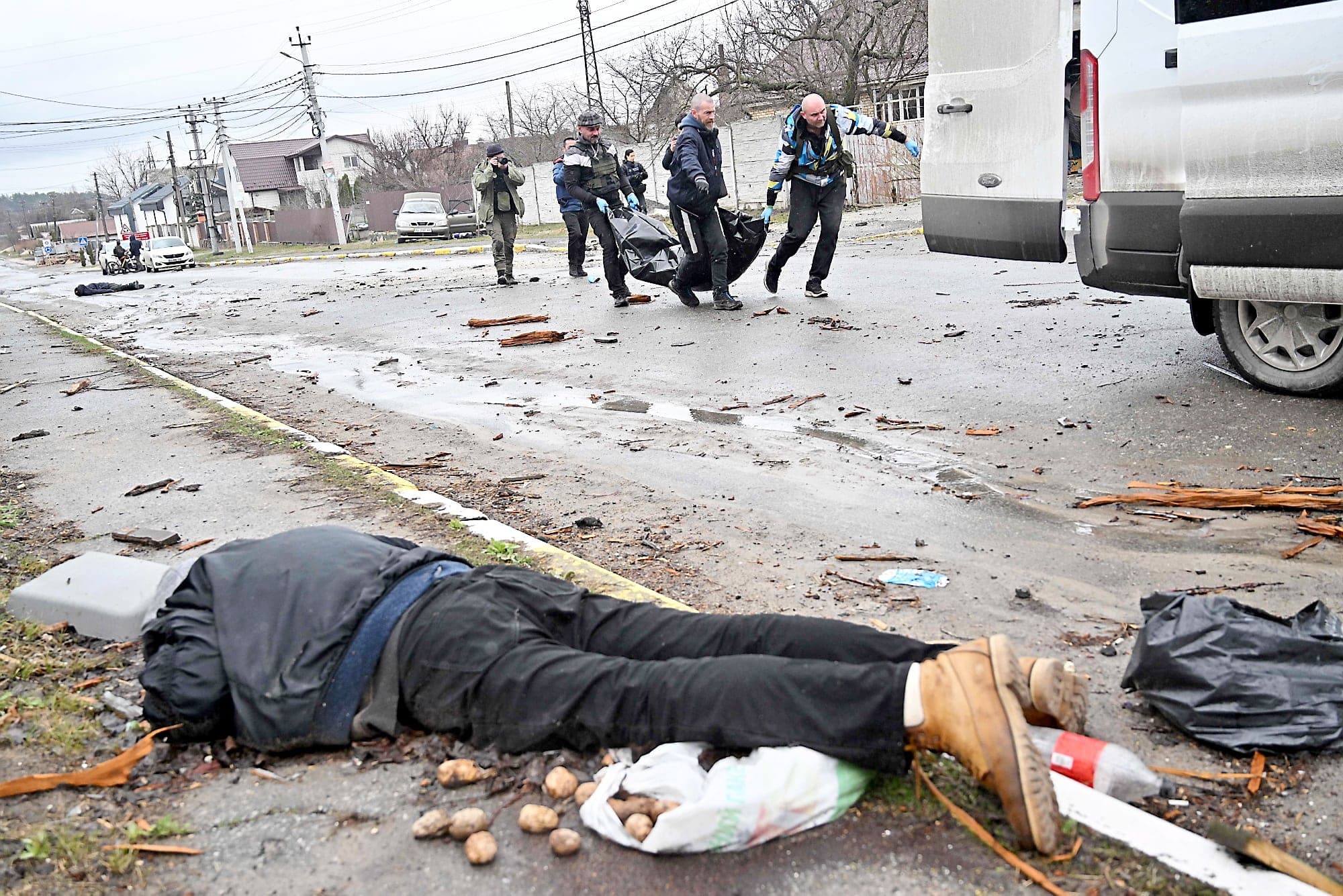 Des bénévoles s’affairent à ramasser les corps qui traînent dans les rues de Boutcha dimanche près du cadavre d’un homme qui transportait des pommes de terre avant d’être tué.