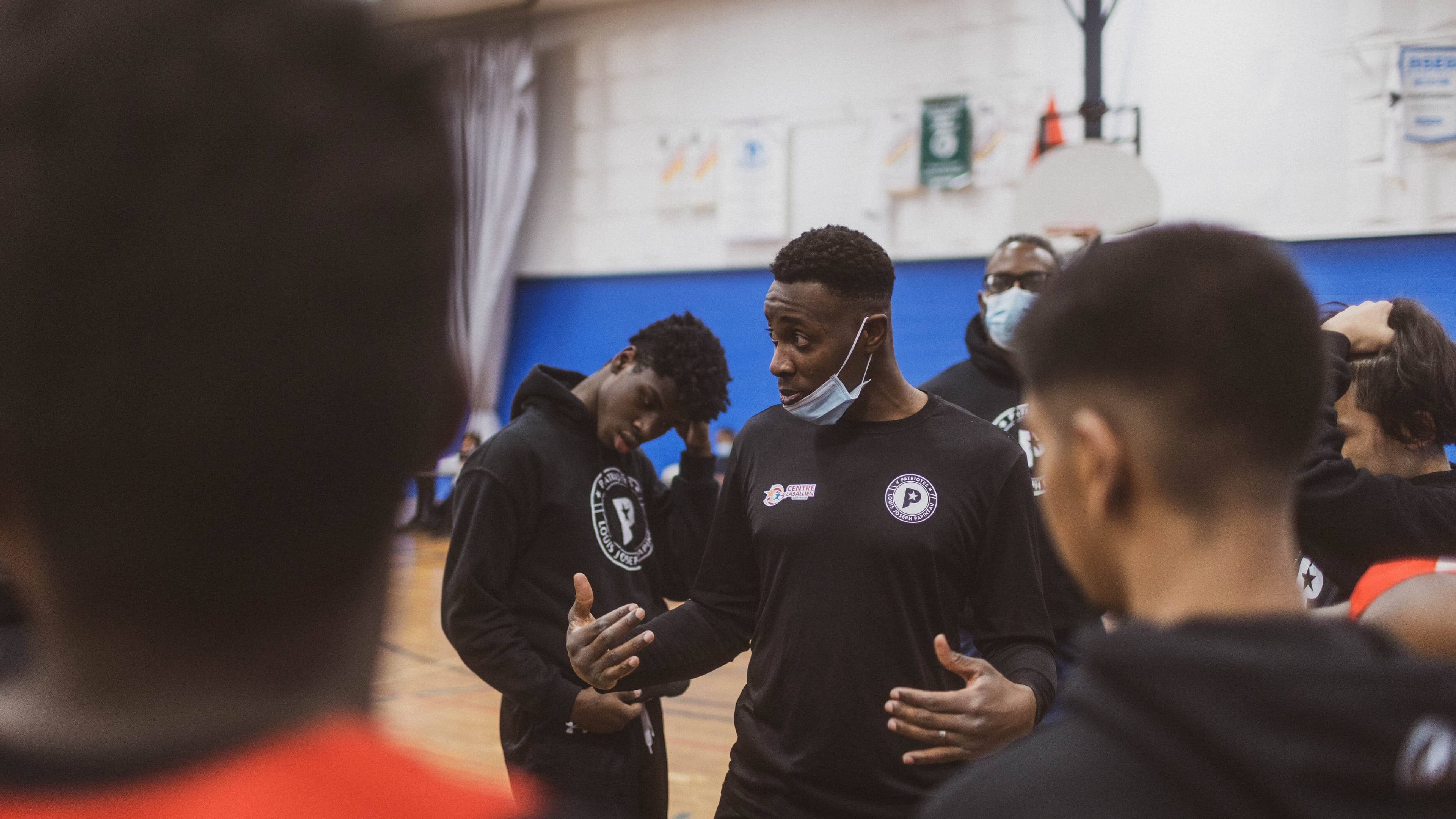 Le basketteur Manix Auriantal parle avec des jeunes à l'école secondaire Louis-Joseph-Papineau dans le quartier Saint-Michel, à Montréal.